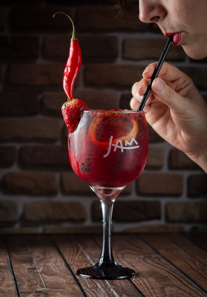 Woman Drinking a Red Cocktail with a Straw